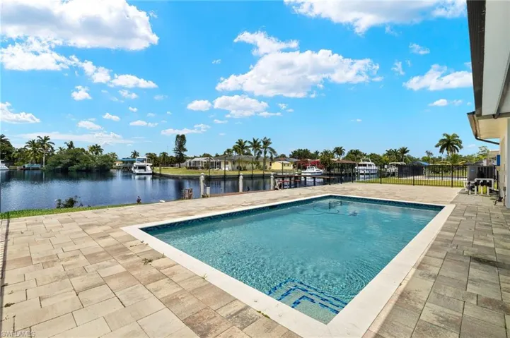 Swimming pool featuring a patio, a water view, and fence