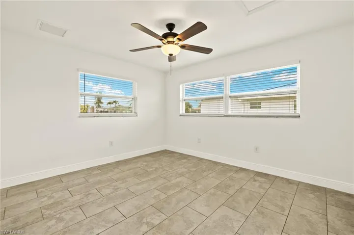 Unfurnished room featuring a ceiling fan, baseboards, and light tile patterned floors