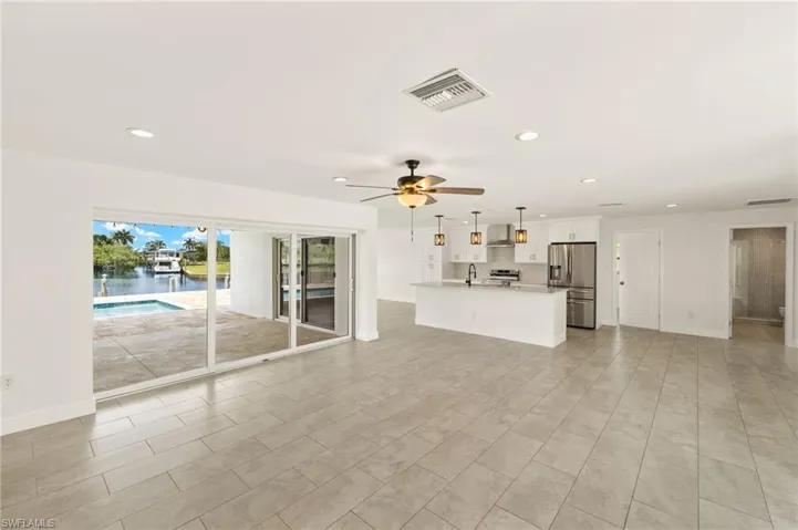 Unfurnished living room with a sink, a ceiling fan, recessed lighting, baseboards, and a water view