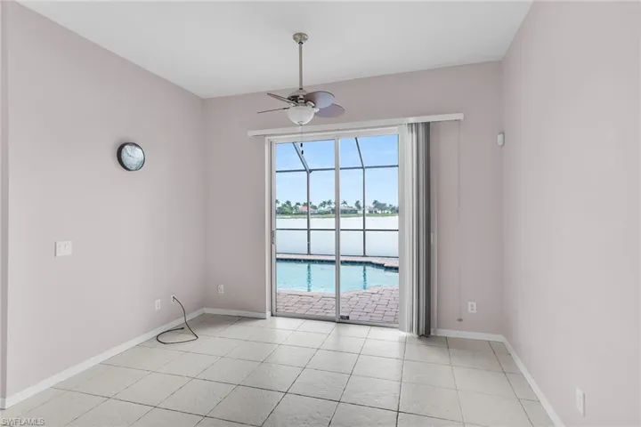 Empty room with a water view, a ceiling fan, light tile patterned floors, and a sunroom