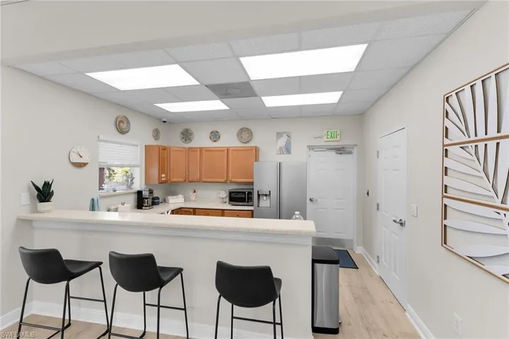 Kitchen with light countertops, light wood-type flooring, stainless steel refrigerator with ice dispenser, a peninsula, and a kitchen breakfast bar