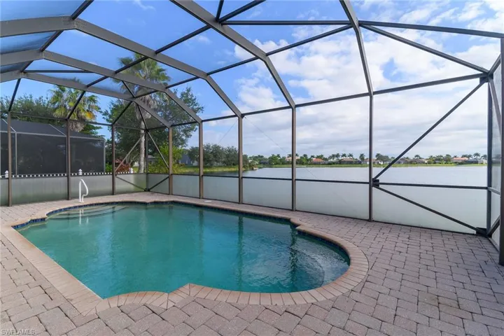 Outdoor pool featuring glass enclosure, a water view, a sunroom, and a patio area