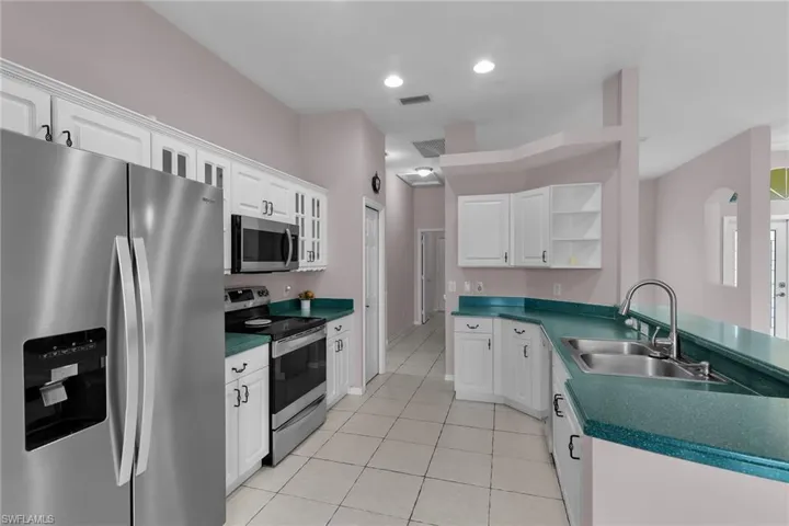 Kitchen with appliances with stainless steel finishes, open shelves, dark countertops, white cabinets, and recessed lighting
