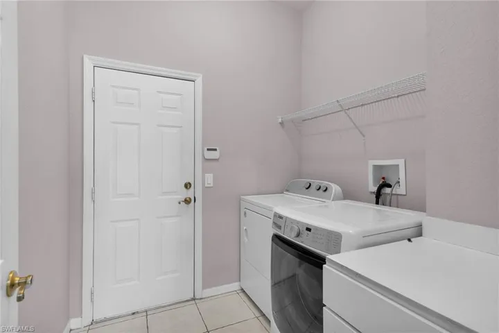 Washroom with light tile patterned floors and independent washer and dryer