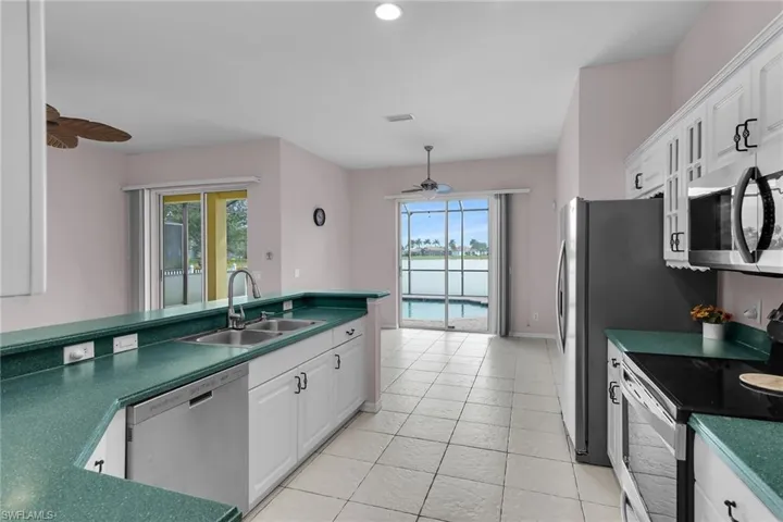 Kitchen with stainless steel appliances, white cabinetry, a ceiling fan, dark countertops, and recessed lighting