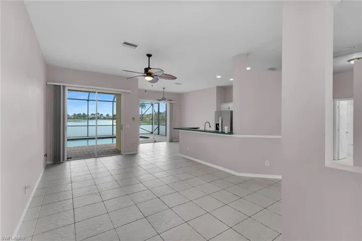 Empty room featuring a water view, a ceiling fan, light tile patterned floors, and recessed lighting