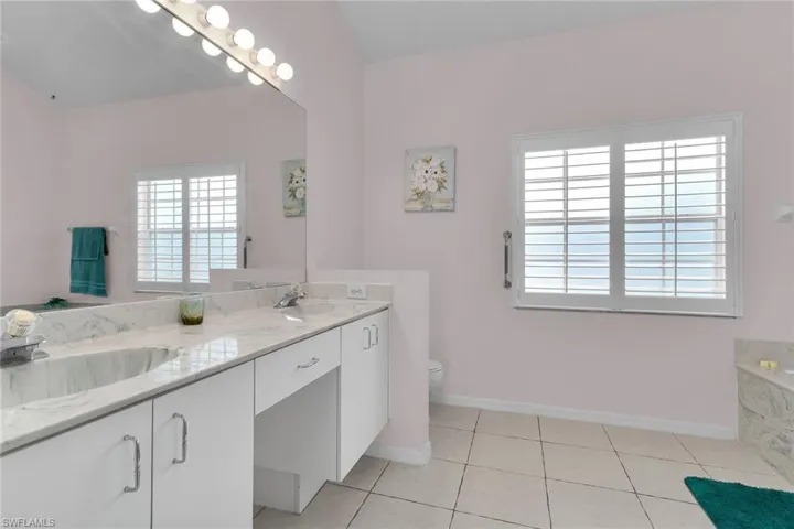 Full bath featuring double vanity, light tile patterned floors, plenty of natural light, and a bath