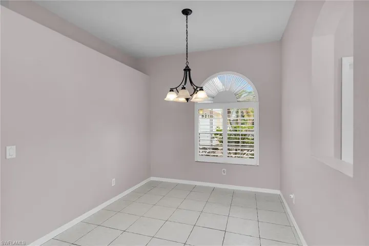 Empty room featuring light tile patterned floors and a chandelier
