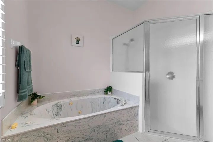 Bathroom featuring a bath, a stall shower, and light tile patterned flooring