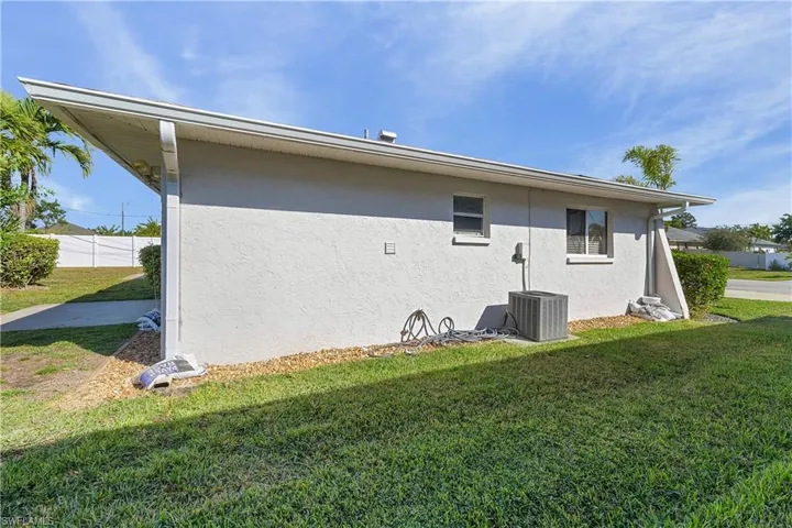 Left side of exterior featuring lawn, stucco siding & w/ac