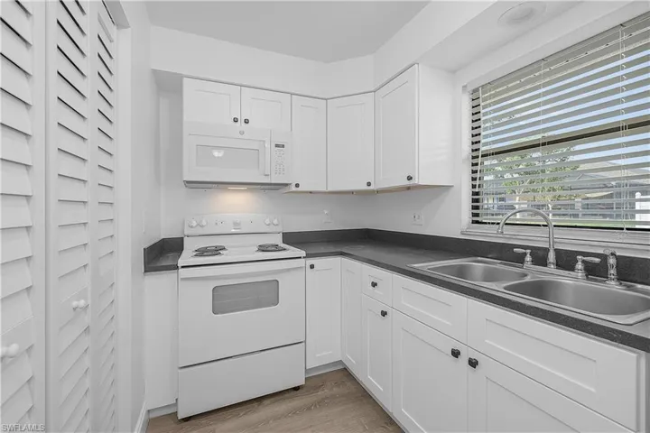 4012(R) Kitchen with white appliances, dark countertops, new white shaker cabinets, and new LVP wood plank flooring