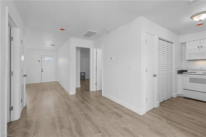 4012(R) Kitchen white appliances, new white shaker cabinetry, and light LVP wood plank flooring