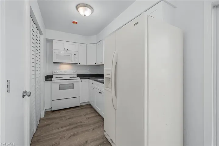 4012(R) Kitchen with white appliances, dark countertops, new white shaker cabinets, and new LVP wood plank flooring
