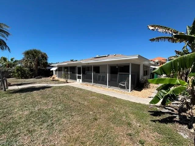 Back of house with a yard and a sunroom