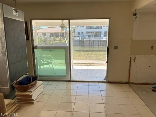 Doorway with light tile patterned flooring and a ceiling fan