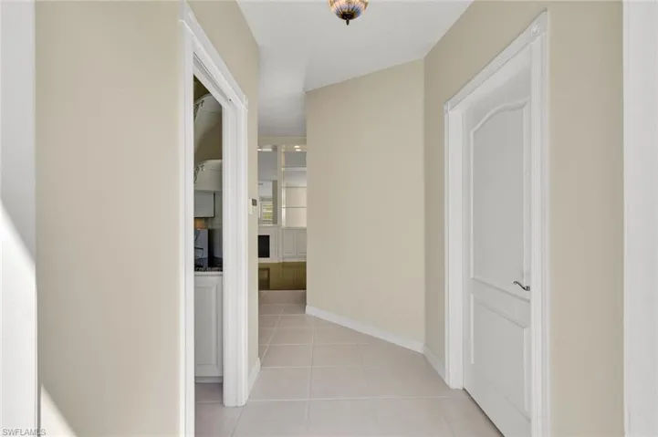 Tiled flooring, neutral wall tones, decorative ceiling light fixture, and white trim