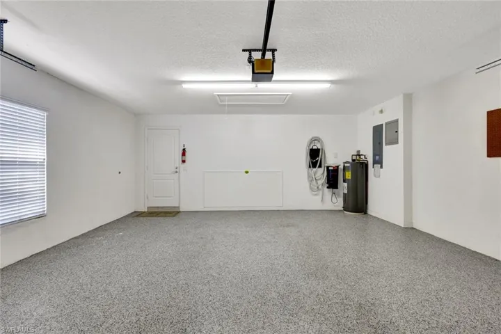 Spacious garage featuring a finished epoxy floor, fluorescent lighting, and a white paneled door