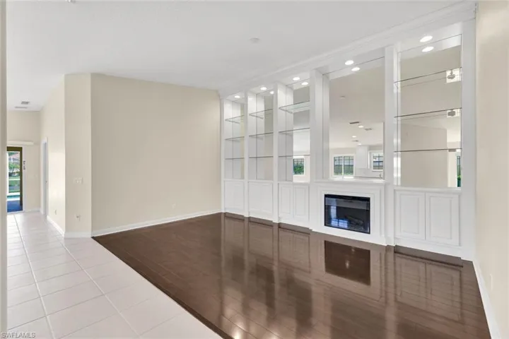 Built-in shelving with glass shelves, integrated fireplace, recessed lighting, and wood-finish flooring