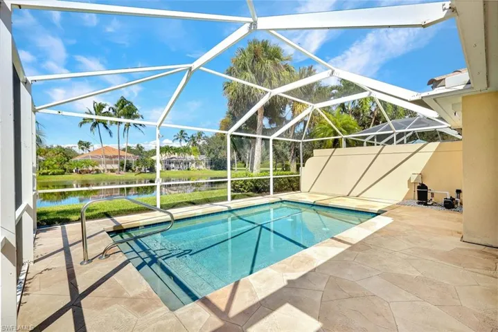 Screened enclosure featuring a rectangular pool with integrated steps, stainless steel handrail, and flagstone-style pool deck