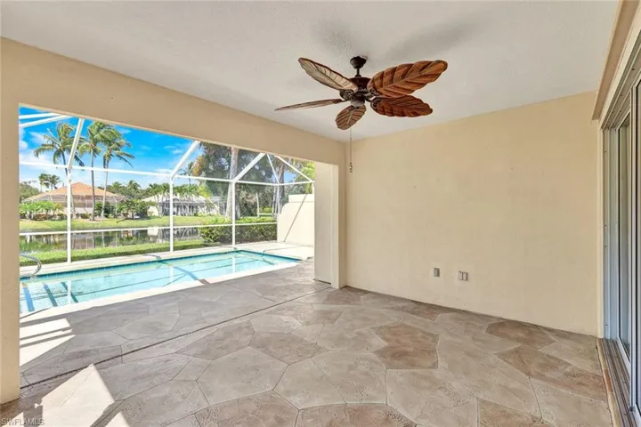 Screened outdoor living area featuring a rectangular pool, textured patio flooring, and a ceiling fan