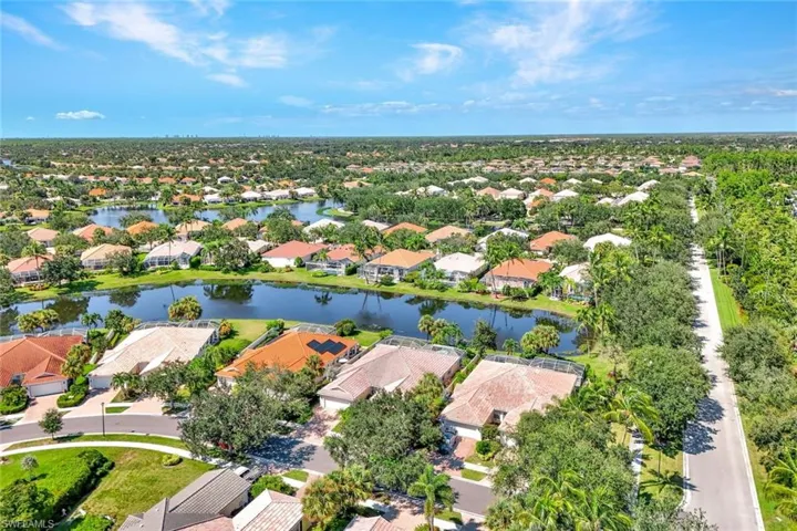 Expansive residential development featuring numerous homes with varied roof styles, multiple water features, and abundant mature trees