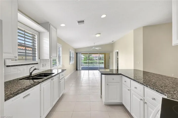 Kitchen with white cabinetry, dark speckled countertops, and a dual basin sink