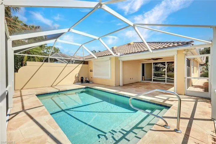 Screened enclosure with an in-ground pool, expansive paved pool deck, and direct access to the interior via sliding glass doors
