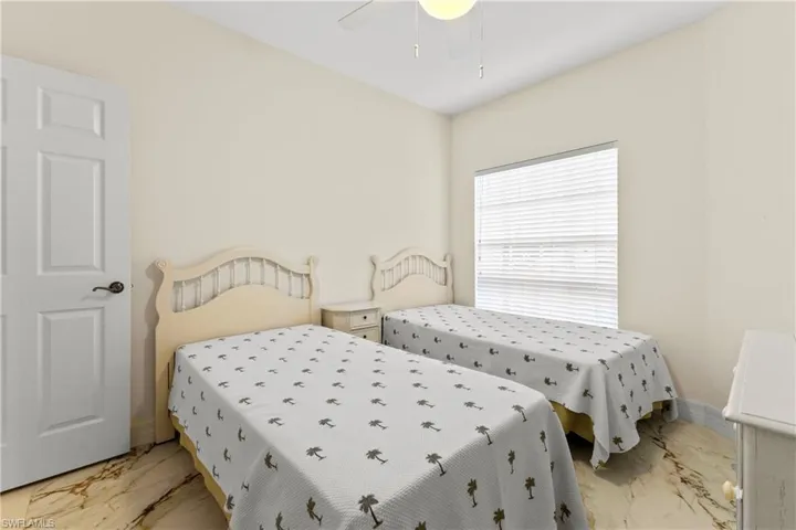 Bedroom featuring light marble finish floors and a ceiling fan