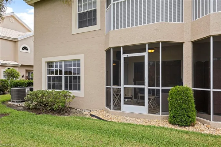 Rear view of house featuring stucco siding, a sunroom, and a yard