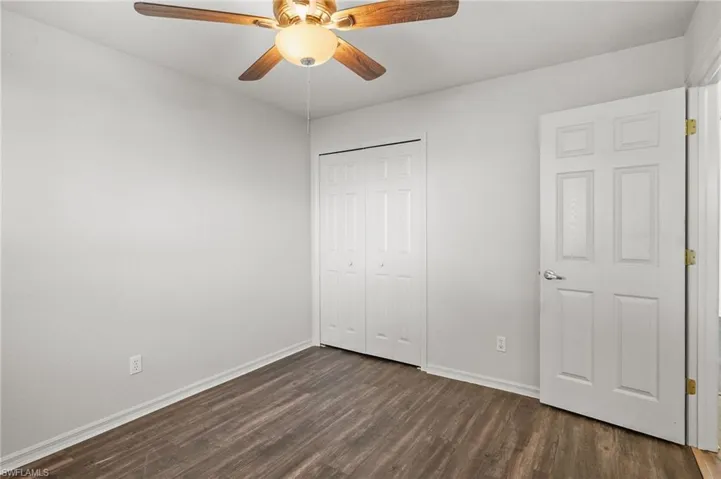 Unfurnished bedroom with dark wood finished floors, a closet, and a ceiling fan