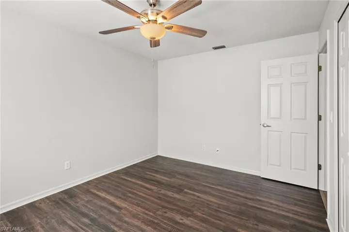 Unfurnished room with dark wood-style floors and ceiling fan