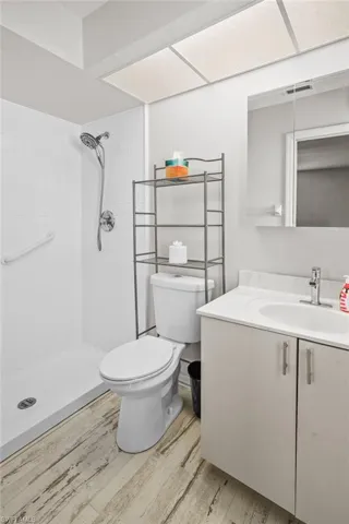 Bathroom with wood finished floors, tiled shower, and vanity