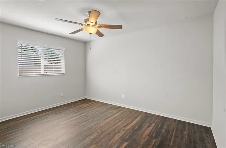 Empty room featuring dark wood-type flooring and ceiling fan