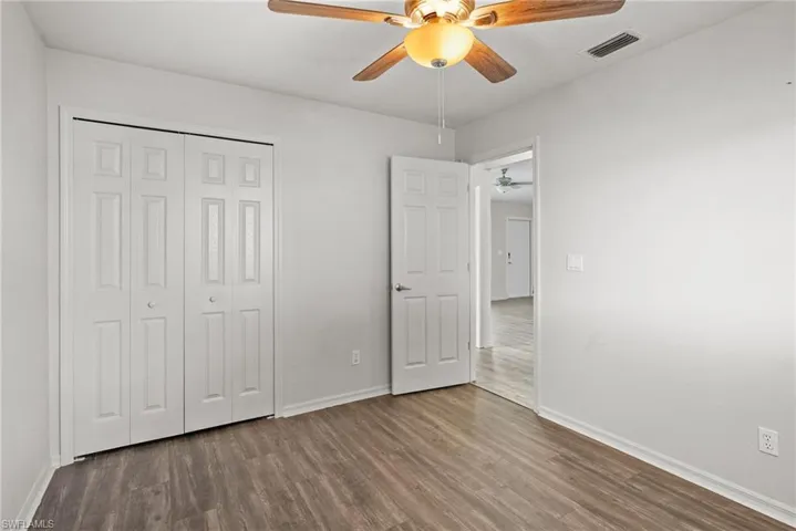 Unfurnished bedroom featuring wood finished floors, a closet, and a ceiling fan