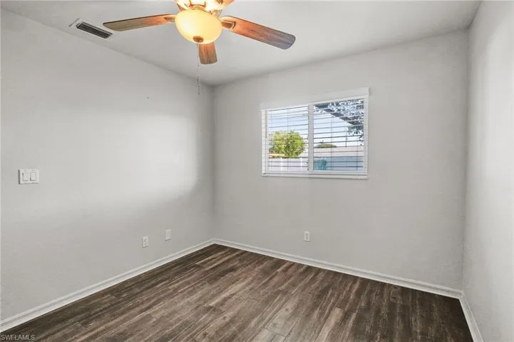 Unfurnished room featuring dark wood-style floors and a ceiling fan