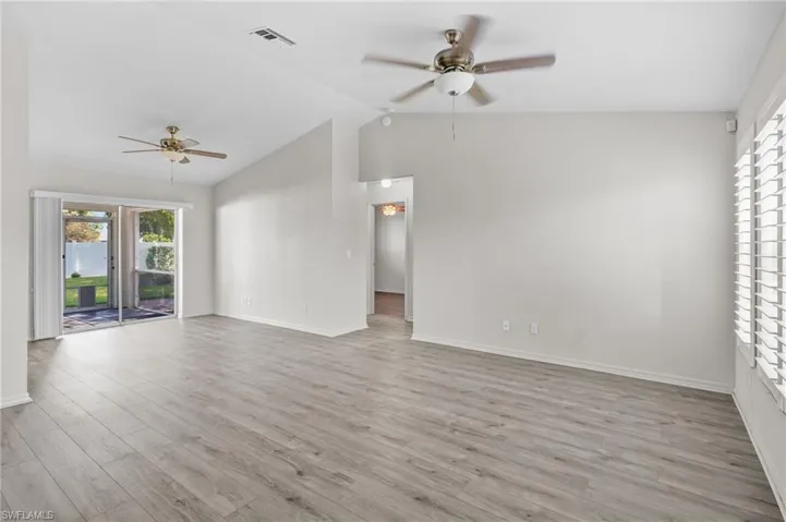 Unfurnished living room with a ceiling fan, lofted ceiling, and wood finished floors