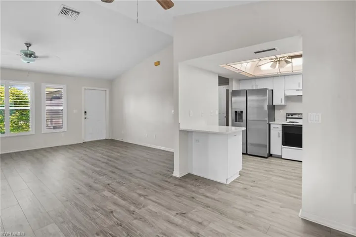 Kitchen with a ceiling fan, stainless steel fridge with ice dispenser, lofted ceiling, light countertops, and white electric range oven
