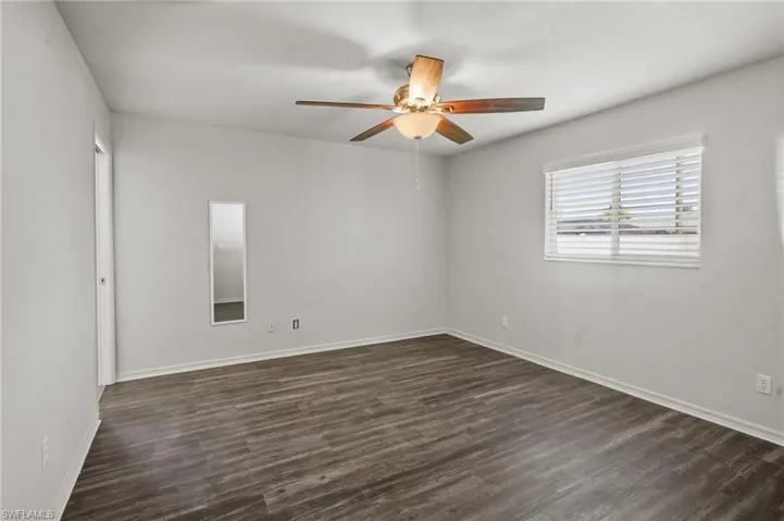 Empty room with a ceiling fan and dark wood-style flooring