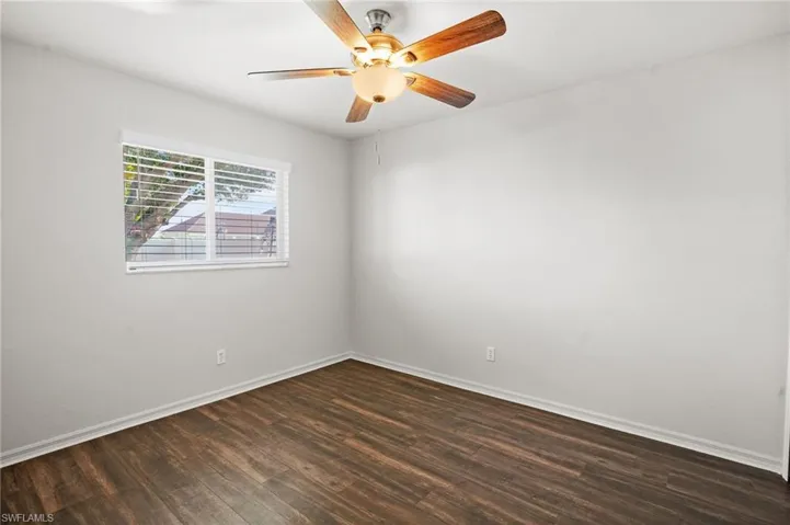 Empty room with dark wood-style floors and a ceiling fan