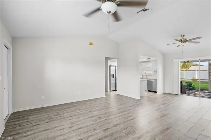 Kitchen with lofted ceiling, a ceiling fan, light countertops, stainless steel appliances, and white cabinets