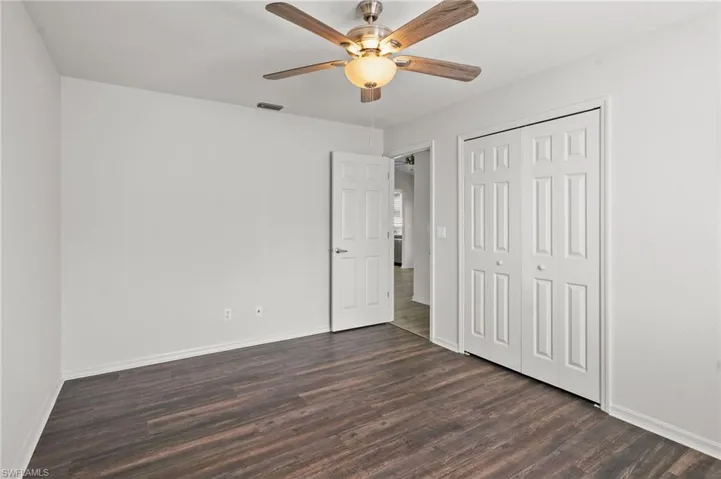 Unfurnished bedroom with dark wood-type flooring, a closet, and ceiling fan