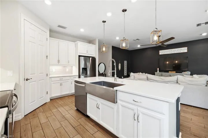 Kitchen featuring hanging light fixtures, white cabinets, appliances with stainless steel finishes, wood finish floors, and recessed lighting