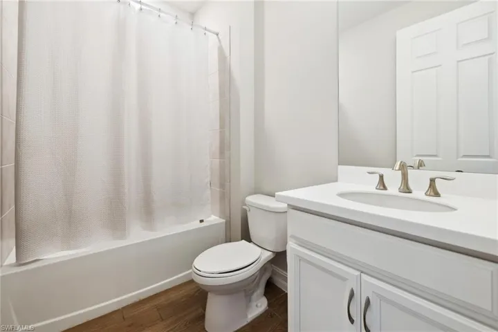 Full bathroom featuring shower / bath combo, vanity, and dark wood-style flooring