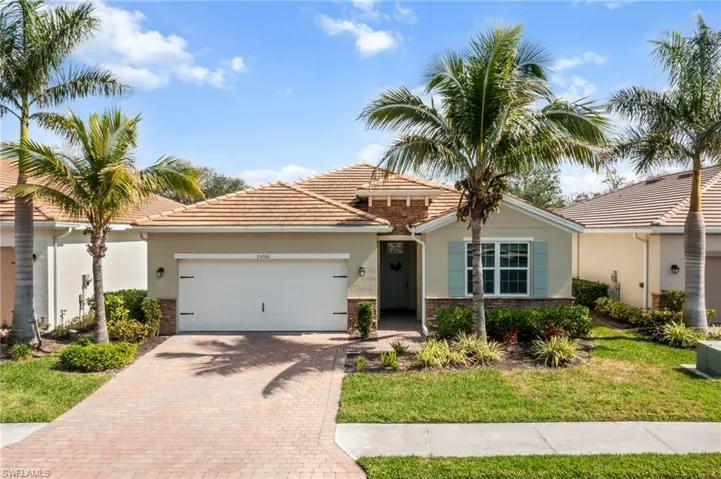 View of front of property with stucco siding, decorative driveway, an attached garage, a front yard, and stone siding