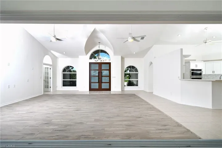 Unfurnished living room featuring built in shelves, french doors, light hardwood / wood-style flooring, and high vaulted ceiling