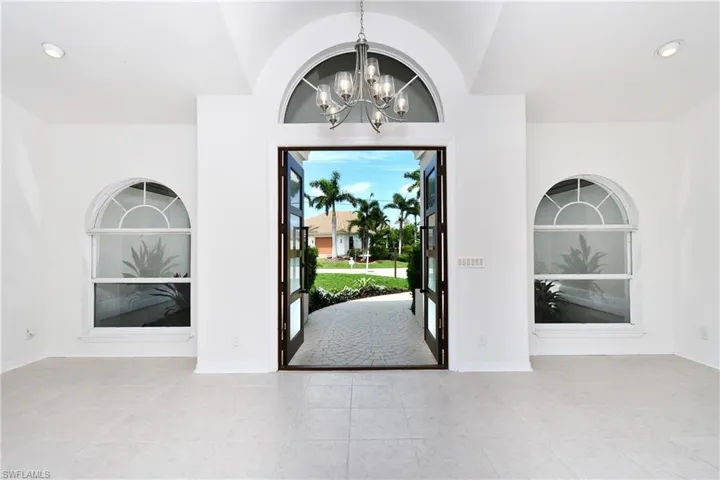 Entrance foyer with a chandelier, vaulted ceiling, and light tile patterned flooring