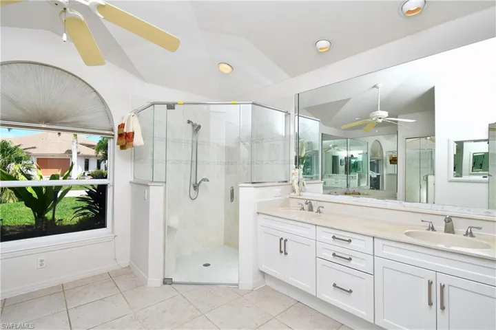 Bathroom featuring walk in shower, vanity, tile patterned flooring, and ceiling fan