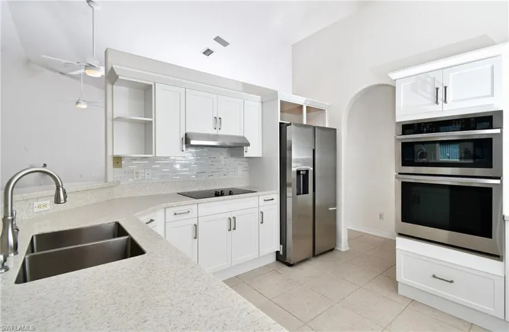 Kitchen with light stone countertops, appliances with stainless steel finishes, sink, and white cabinets