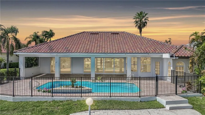 Back house at dusk with a fenced in pool and a patio area