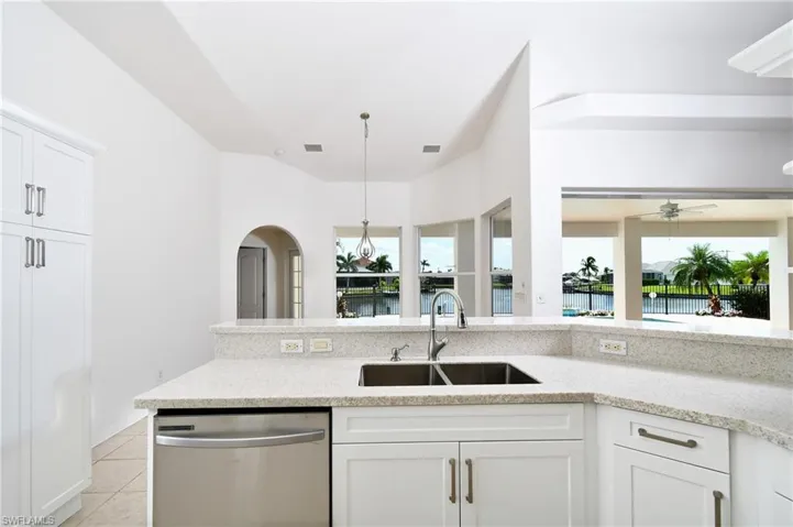 Kitchen with sink, a water view, ceiling fan, stainless steel dishwasher, and white cabinets